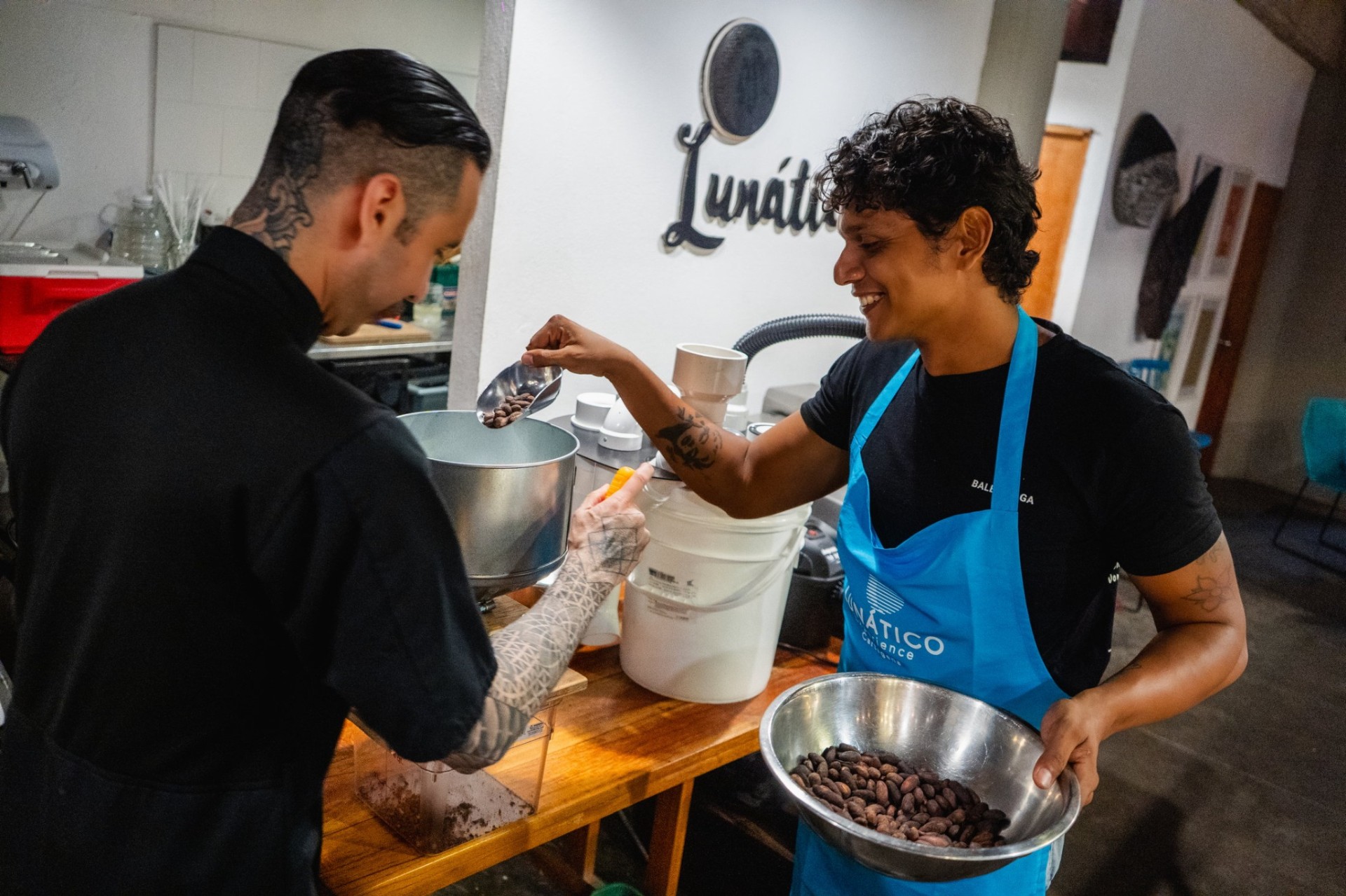Anfitrión y participante interactuando con granos de cacao y materiales de origen en Lunático, Cartagena