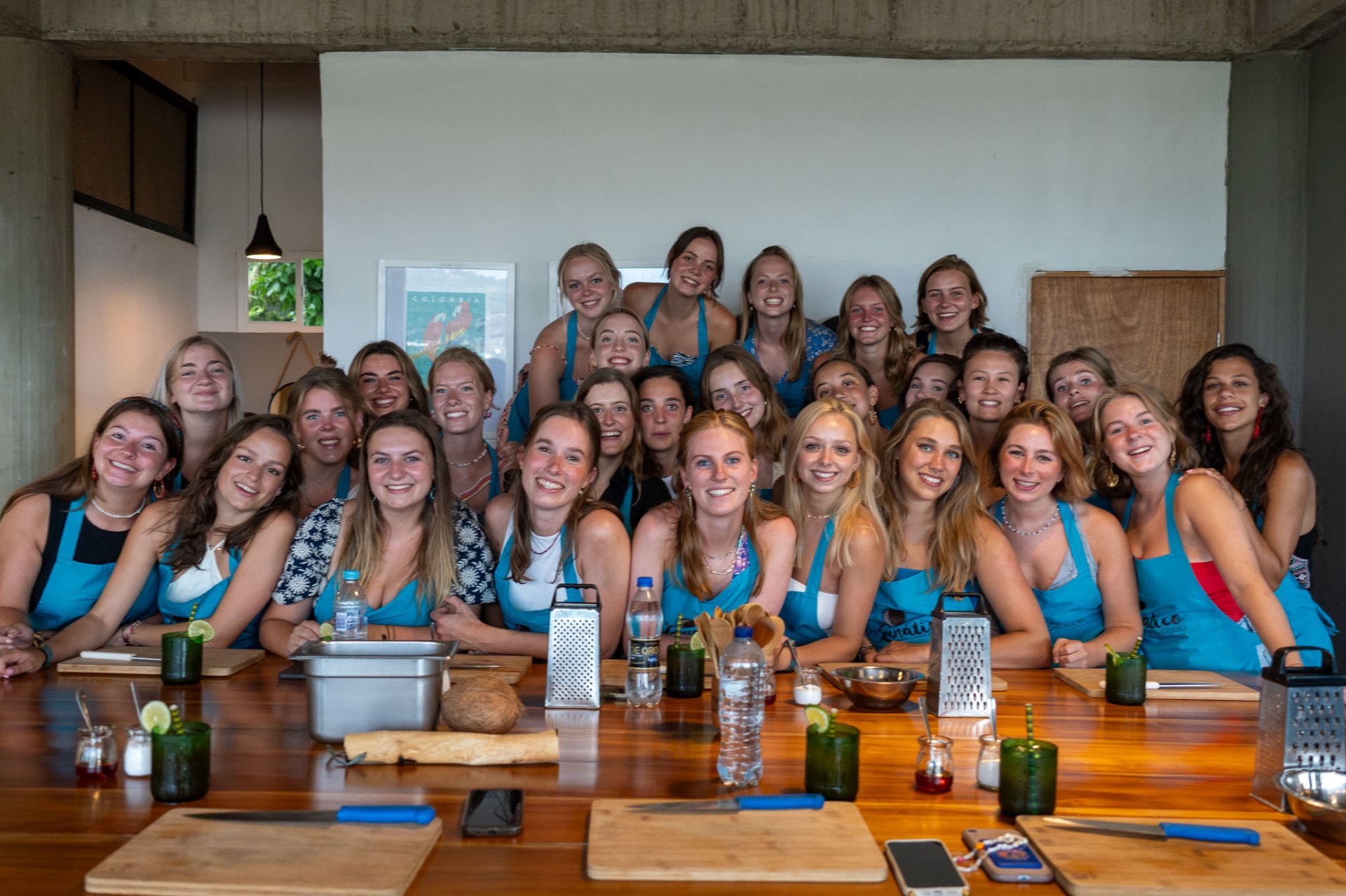 Large private group in Lunático aprons gathered around the cooking table for a private Colombian cooking class in Cartagena